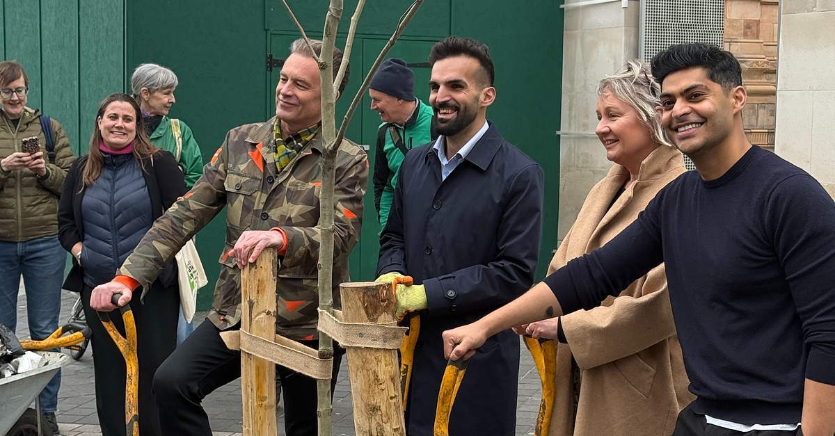 People posing with a recently planted tree
